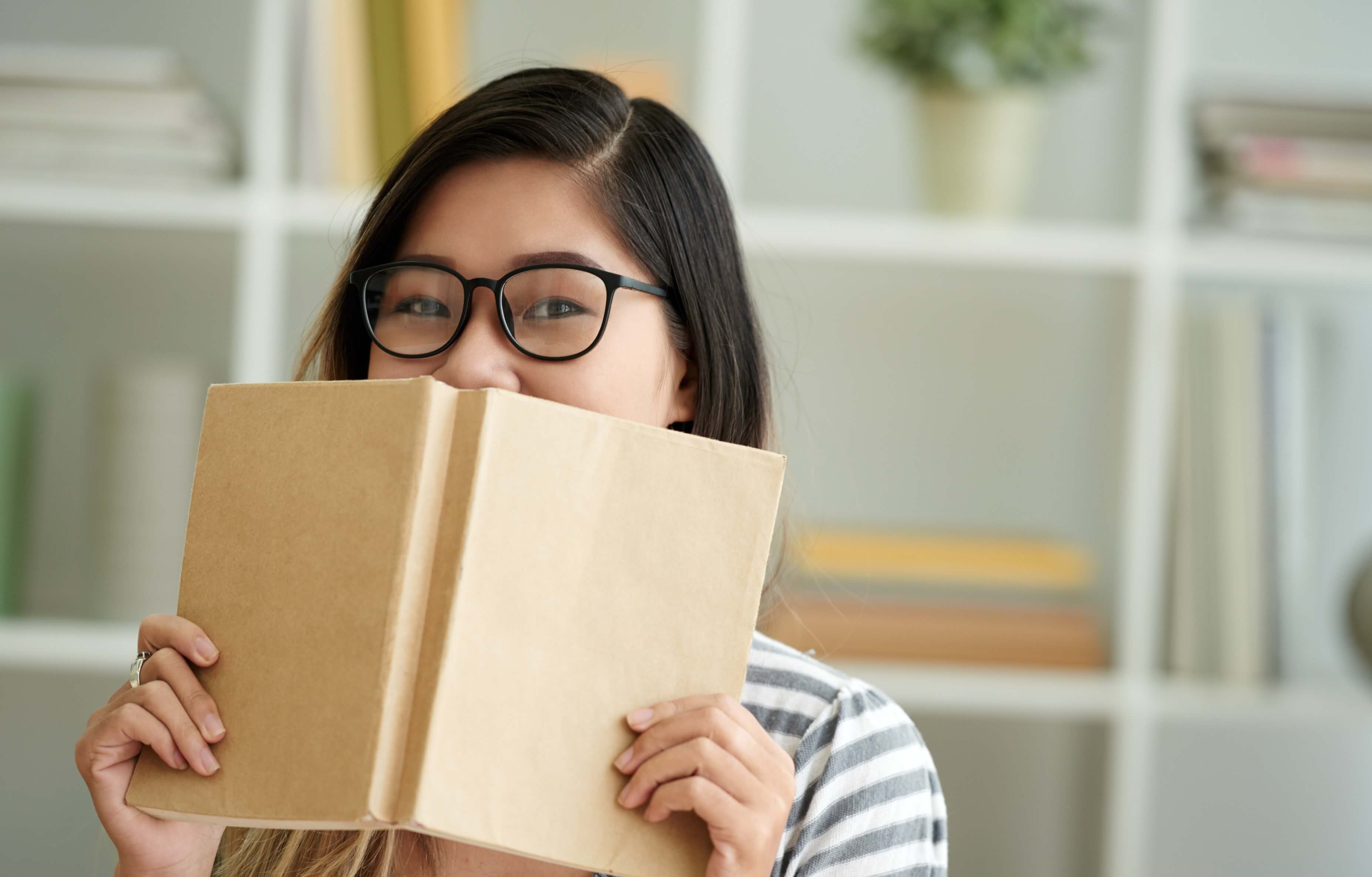 Nursing student with book covering her face