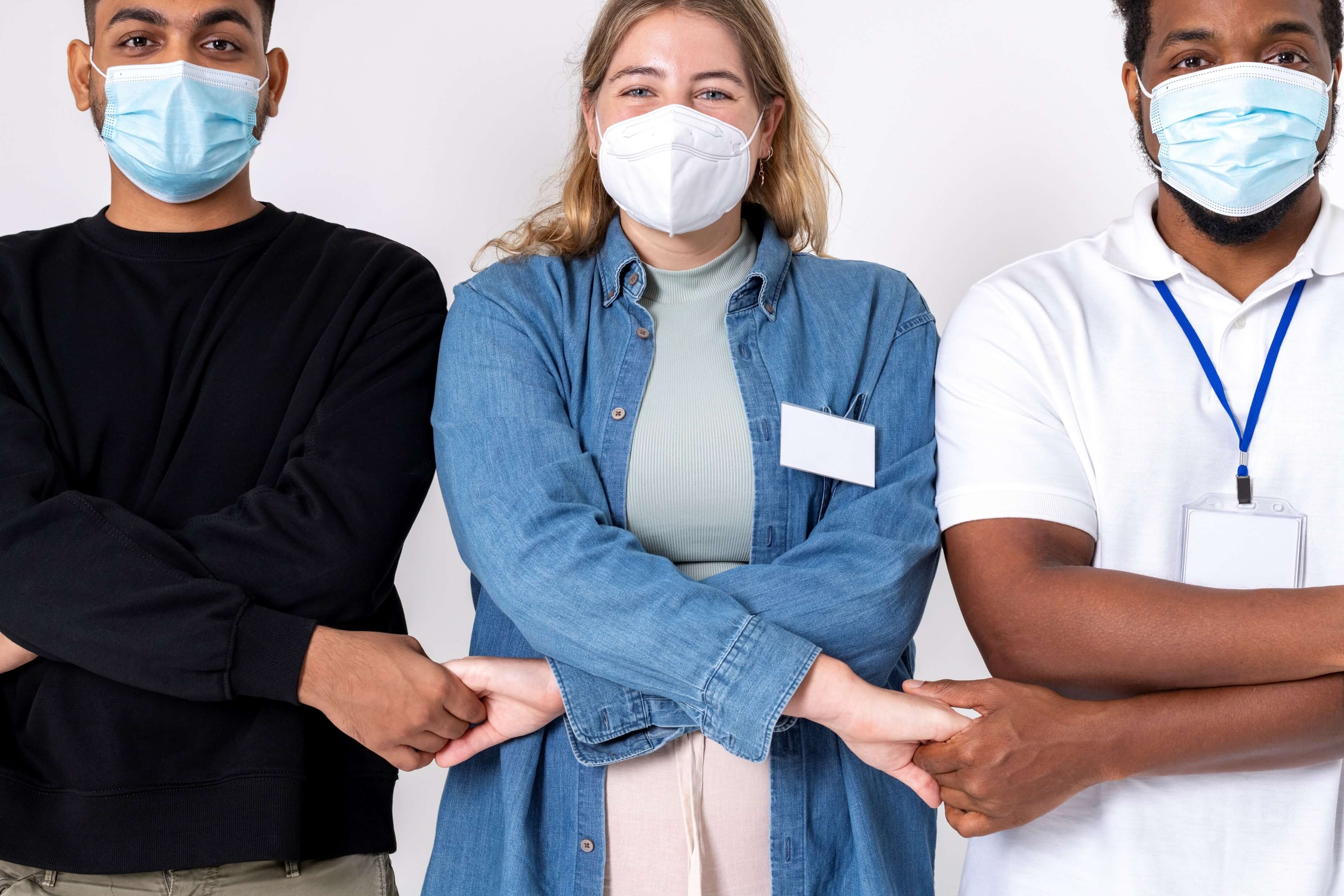 People joining hands wearing masks