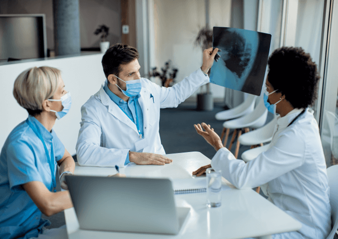 Team of healthcare experts examining x-ray image at medical clinic