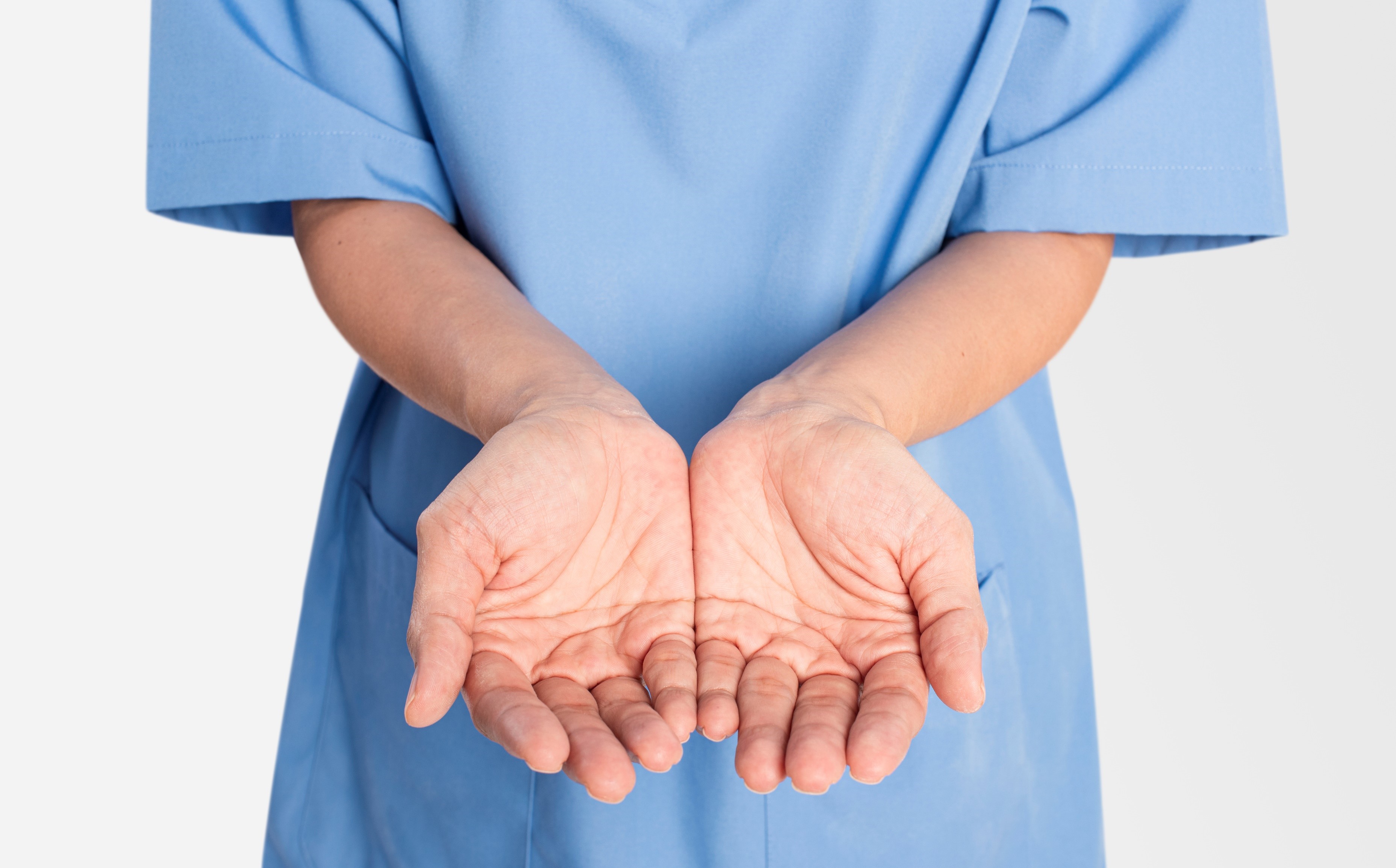Nurse in scrubs with open palms