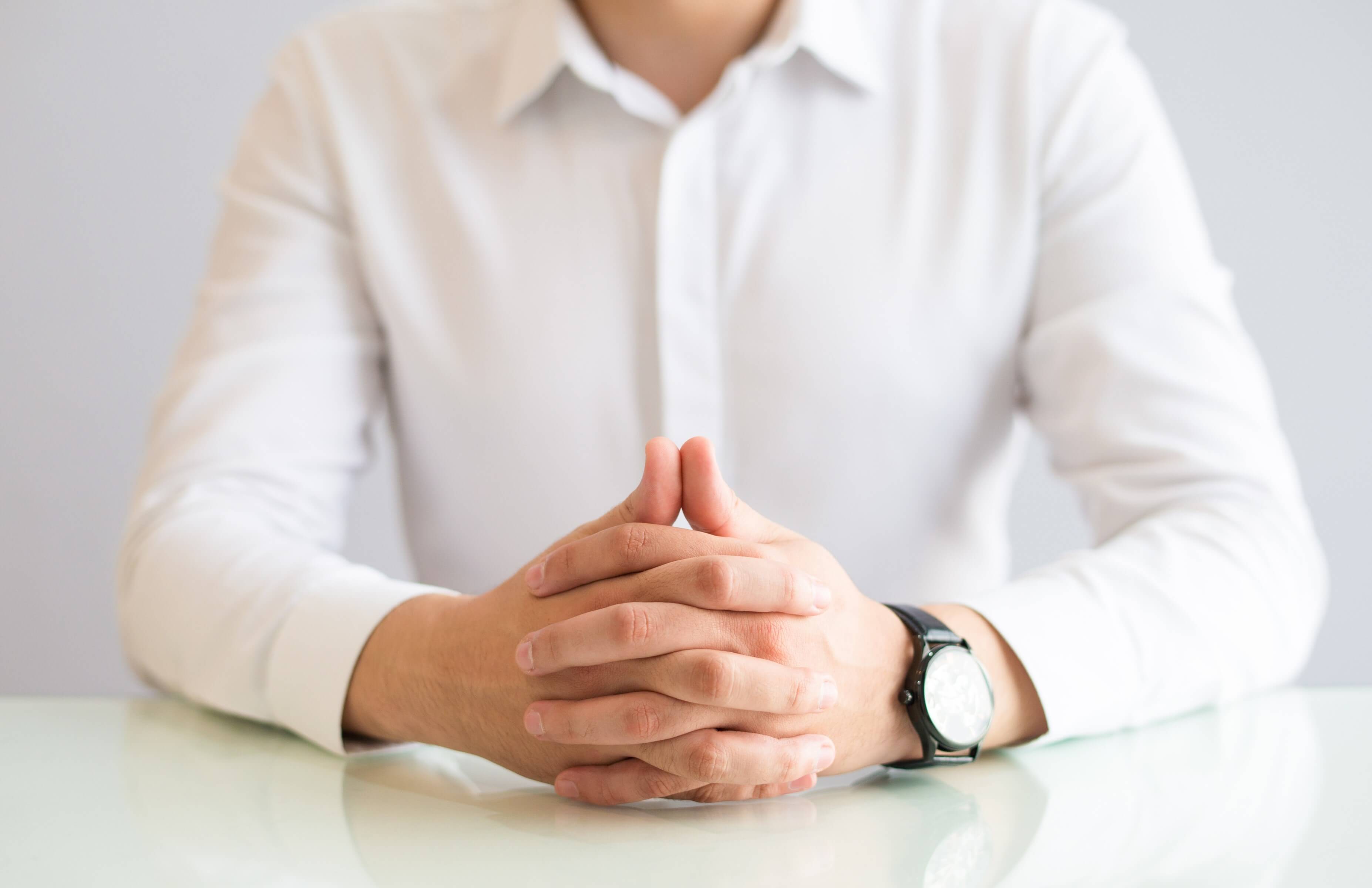 Close up picture of a man with hands clasped