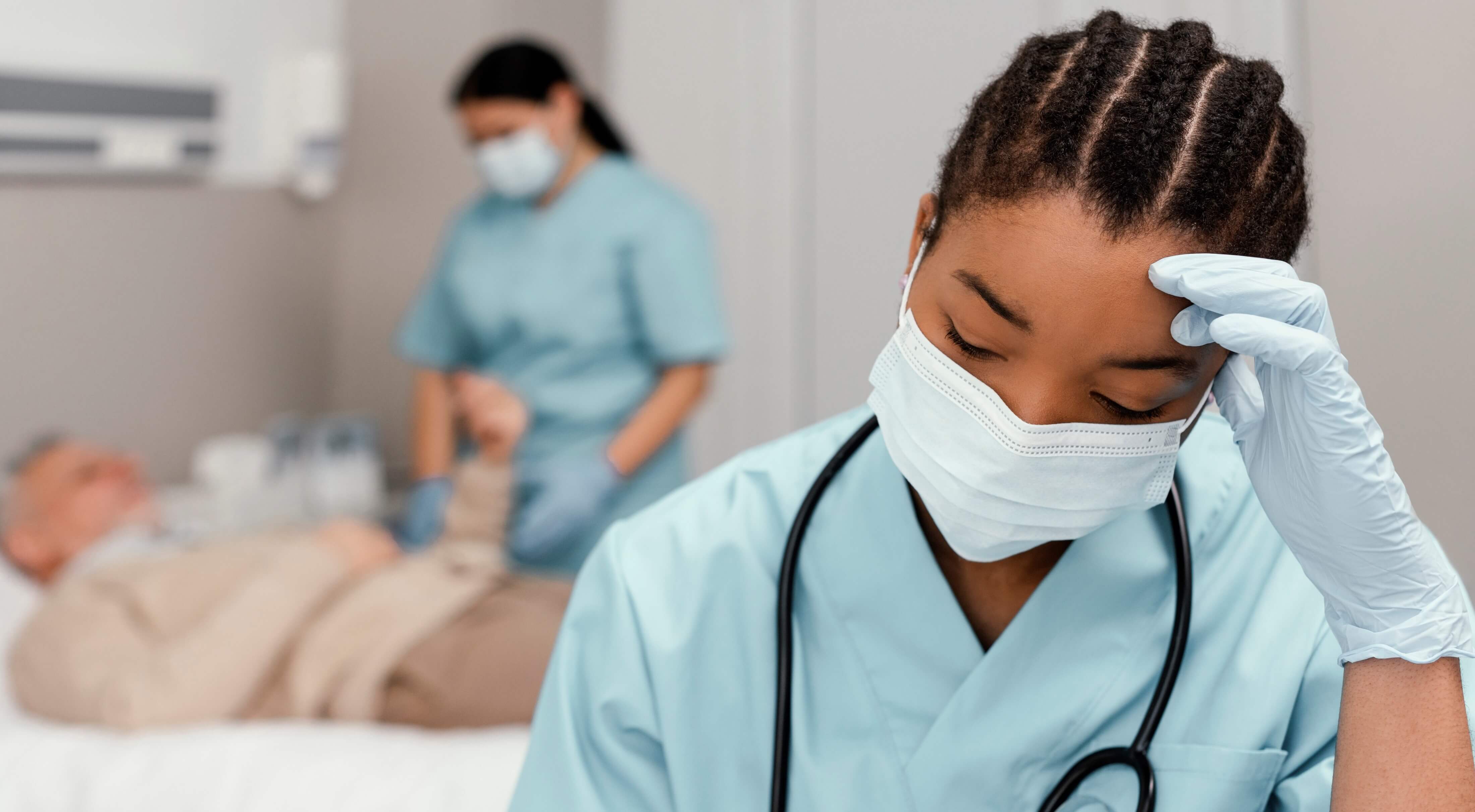 Nurse tired with a medical worker and patient in the background