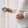 pregnant-woman-standing-by-window-looking-photo